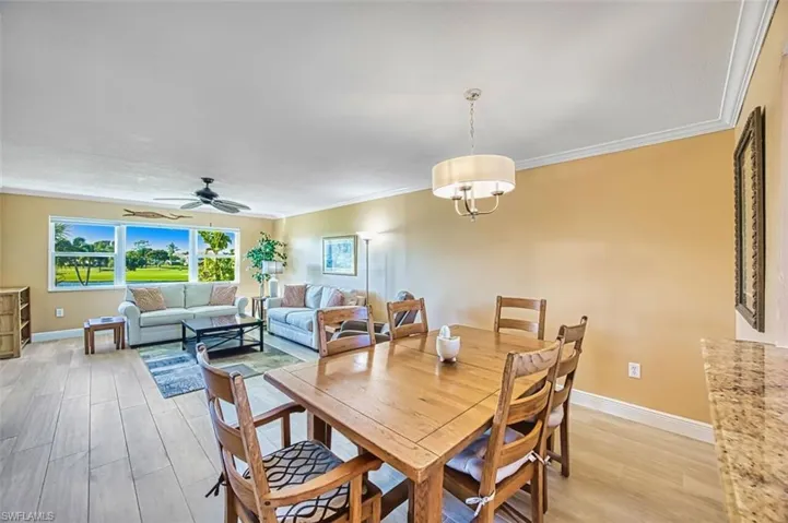 Dining room featuring light wood-style floors, crown molding, and ceiling fan
