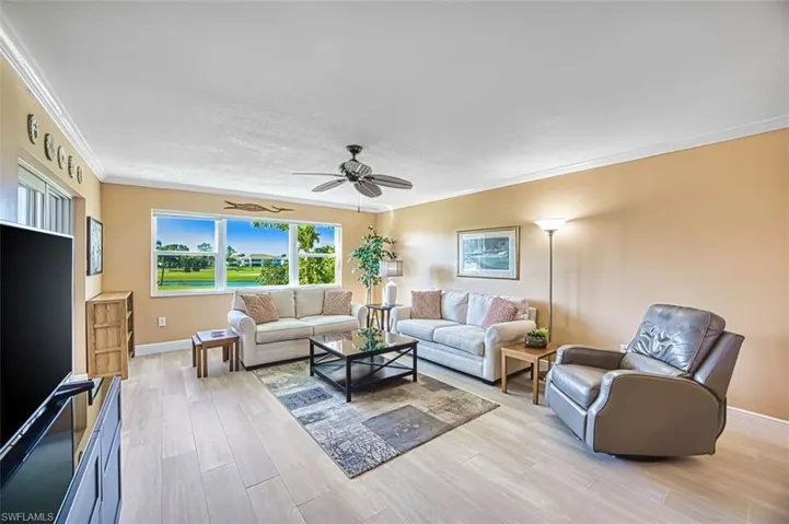 Living area with crown molding, light wood-type flooring, and ceiling fan