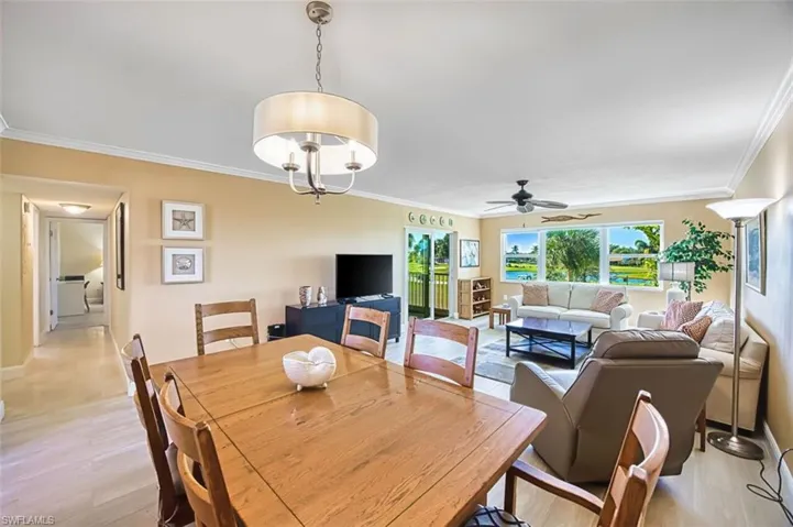 Dining room with crown molding, light wood finished floors, ceiling fan, and a chandelier