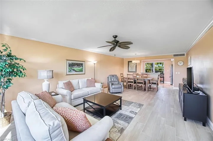 Living room featuring light wood-type flooring, a ceiling fan, and crown molding