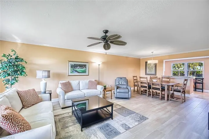 Living room featuring crown molding, wood finished floors, ceiling fan, and a textured ceiling