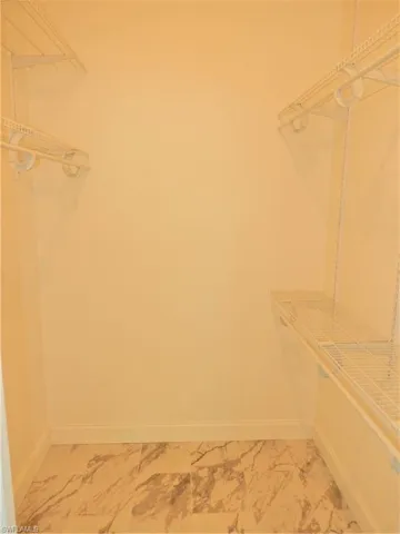 Spacious walk-in master closet featuring tile floors