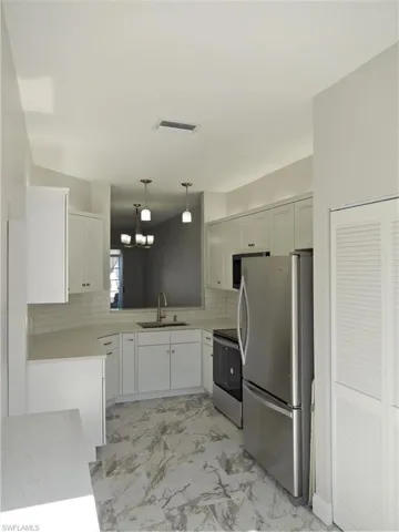 Kitchen featuring sink, white cabinets, stove, and fridge