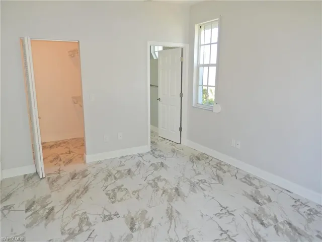 Master suite featuring a walk in closet, a closet, and light tile floors