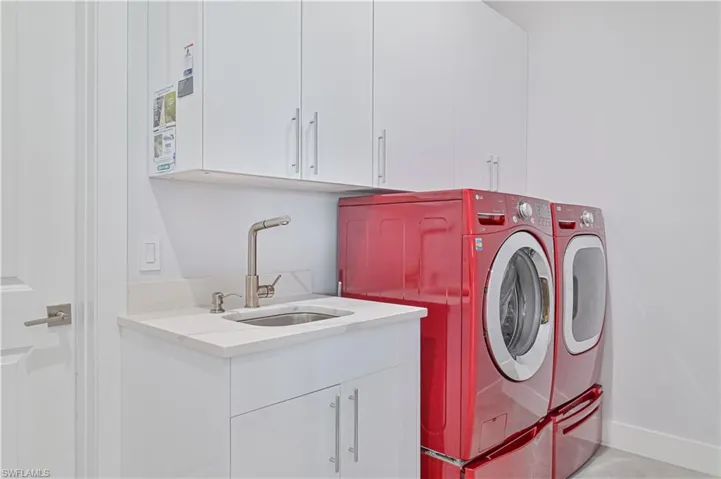 Washroom with a sink, baseboards, cabinet space, and washing machine and dryer