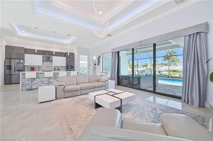 Living room featuring a raised ceiling, marble finish floor, and ornamental molding