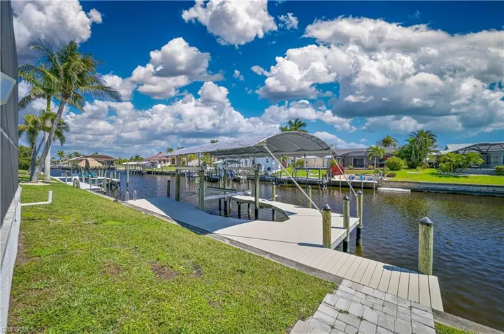 Dock area with boat lift, a residential view, a water view, and a lawn