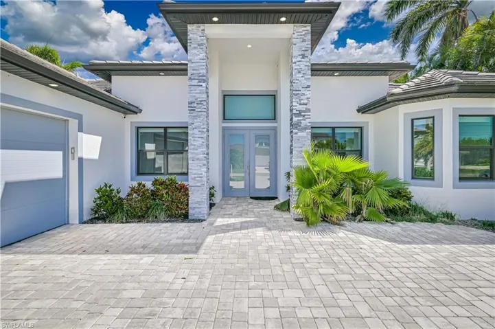Property entrance with stucco siding, an attached garage, and french doors