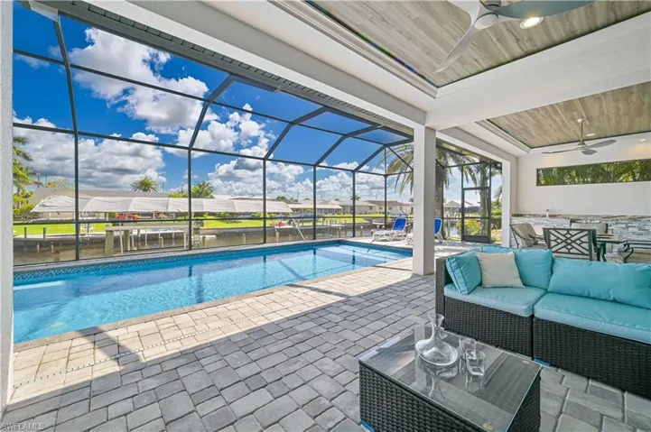 Outdoor pool featuring glass enclosure, an outdoor living space, ceiling fan, and a patio
