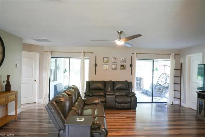 Spacious living area featuring wood-finish flooring, a contemporary ceiling fan, and large sliding glass doors leading to an outdoor space