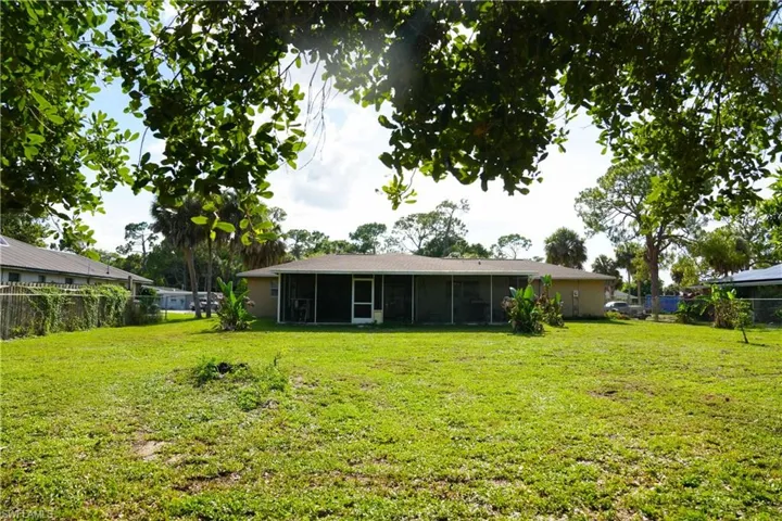 Expansive green lawn with a screened-in rear patio extending across the back of the residence