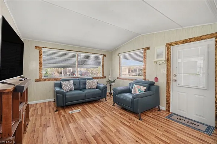 Spacious living area featuring wood-finish flooring, two large windows, and a vaulted ceiling
