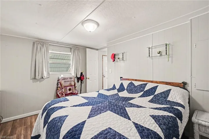 Wood-finish flooring with light gray paneled walls and a built-in overhead light fixture