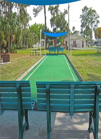Bocce ball court featuring an artificial turf playing surface, perimeter benches, and and overhead sunshade