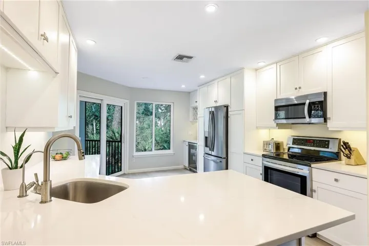 Wine refrigerator and wine rack to the left of the refrigerator, luxury vinyl throughout the main living area, impact windows and doors - there is so much to LOVE about this home!