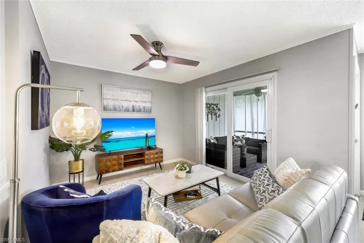Living area with a textured ceiling, ceiling fan, and crown molding