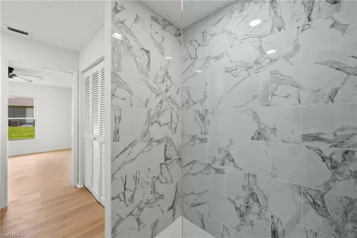 Bathroom featuring a tile shower, ceiling fan, and hardwood / wood-style floors