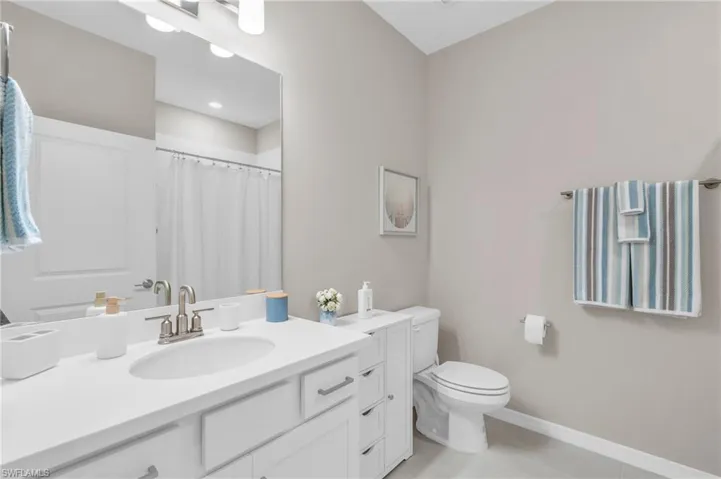 Bathroom with toilet, vanity, a shower with curtain, and tile patterned floors