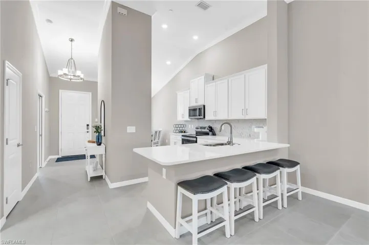 Kitchen with kitchen peninsula, appliances with stainless steel finishes, white cabinetry, and sink