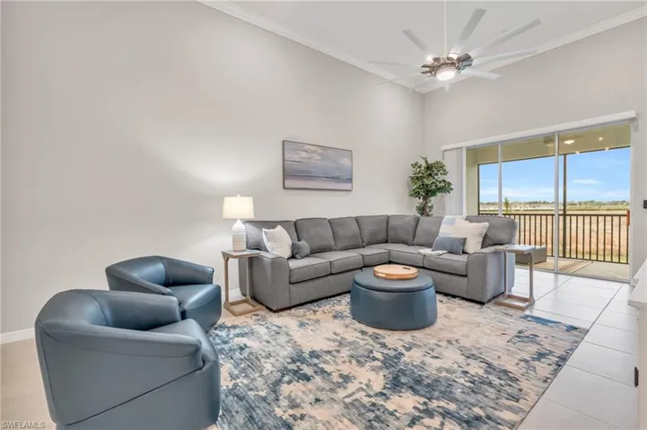 Tiled living room featuring ceiling fan and crown molding