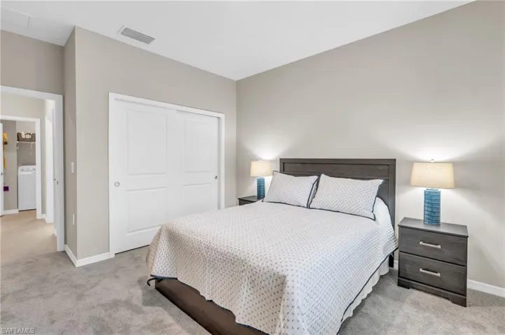 Bedroom featuring a closet, light colored carpet, and washer / clothes dryer