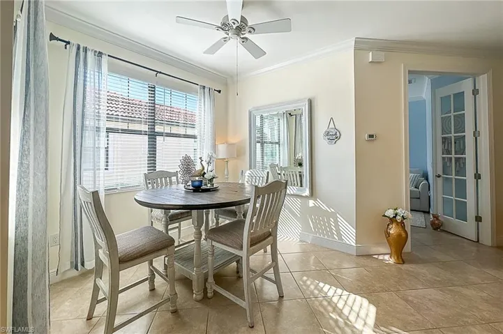Dining room with ornamental molding, ceiling fan, and light tile floors