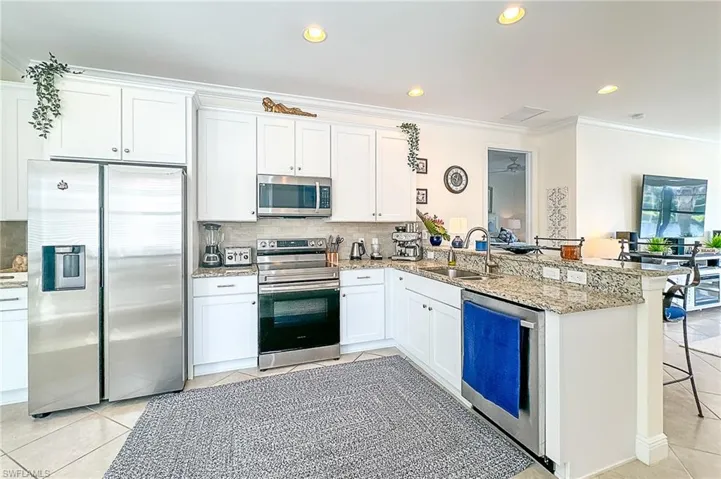 Kitchen with crown molding, appliances with stainless steel finishes, a breakfast bar area, kitchen peninsula, and sink