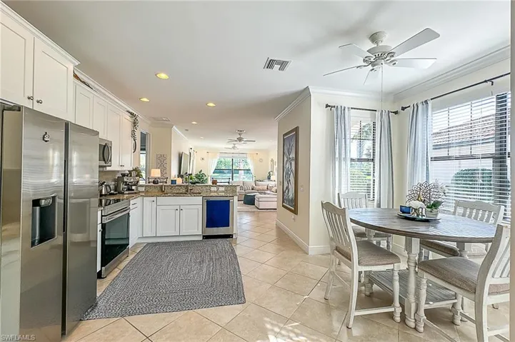 Kitchen featuring kitchen peninsula, stainless steel appliances, ceiling fan, ornamental molding, and light tile floors