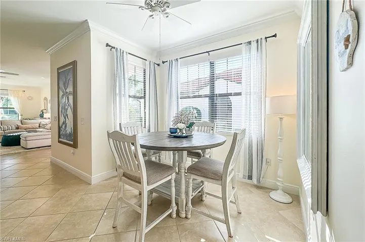 Tiled dining room featuring ornamental molding and ceiling fan