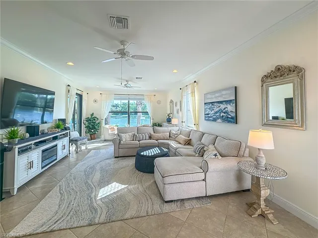 Living room with ceiling fan, light tile floors, and ornamental molding