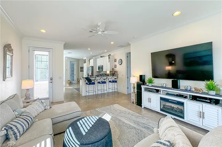 Tiled living room featuring ceiling fan and crown molding