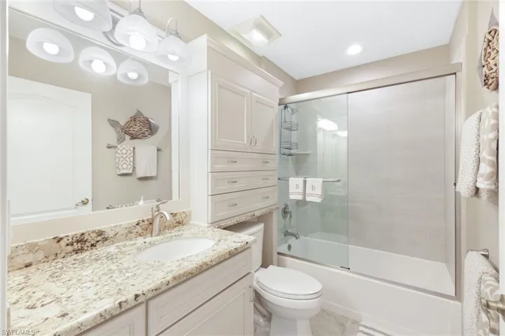 Full bathroom with toilet, enclosed tub / shower combo, and vanity