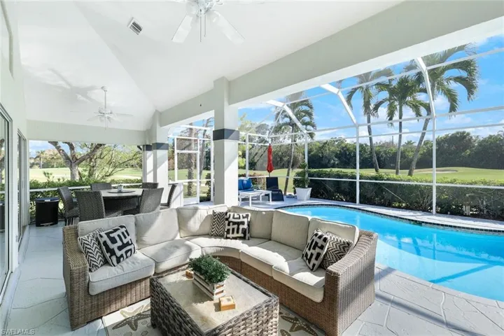 View of swimming pool featuring ceiling fan, glass enclosure, a patio area, and an outdoor hangout area