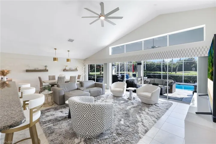 Living room with ceiling fan, high vaulted ceiling, light tile patterned floors, and plenty of natural light