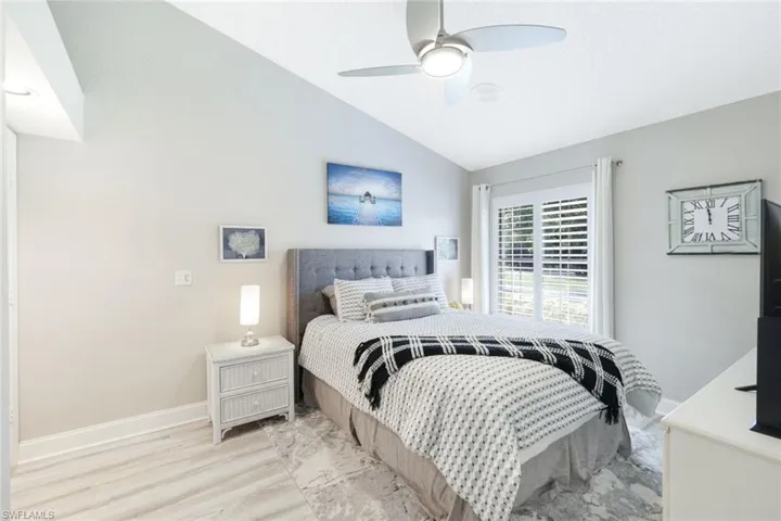 Bedroom with light hardwood / wood-style flooring, vaulted ceiling, and ceiling fan