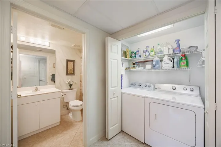 Laundry area with washing machine and dryer and light tile patterned floors