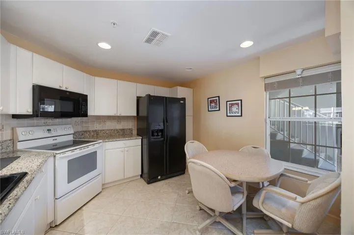 Kitchen featuring black appliances, white cabinets, light stone countertops, decorative backsplash, and recessed lighting