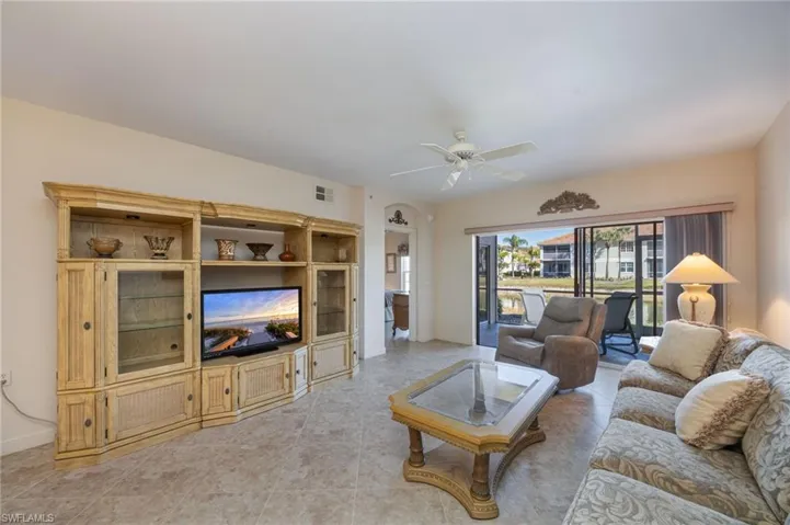 Living room with ceiling fan, arched walkways, and light tile patterned floors