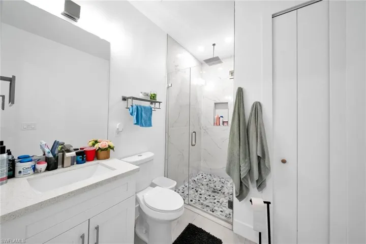 Bathroom featuring vanity, a marble finish shower, and recessed lighting