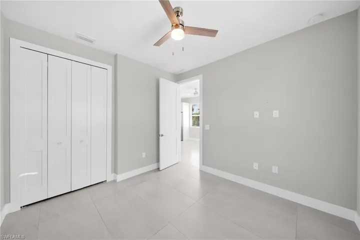 Unfurnished bedroom featuring a ceiling fan, a closet, and light tile patterned flooring