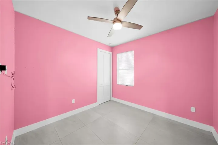 Empty room with ceiling fan and light tile patterned floors