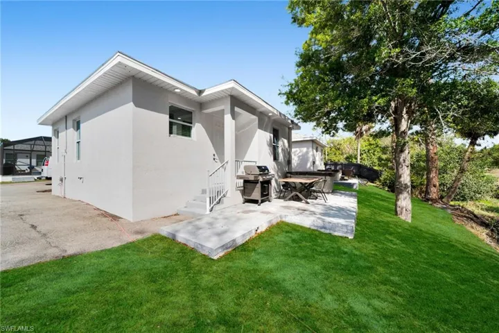 Rear view of house with stucco siding, a lawn, a patio area, and a deck