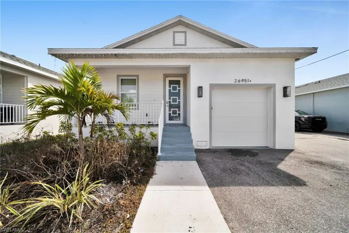 View of front facade with a garage, covered porch, driveway, and stucco siding