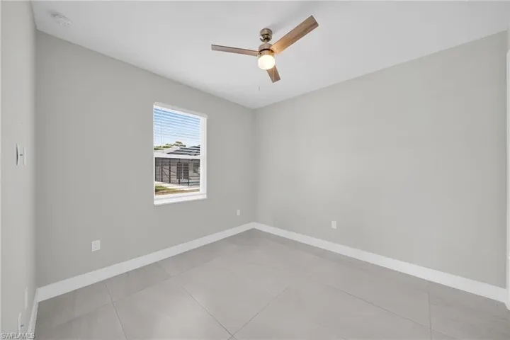 Empty room featuring a ceiling fan and light tile patterned floors