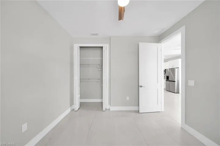 Unfurnished bedroom featuring stainless steel fridge, a closet, and ceiling fan