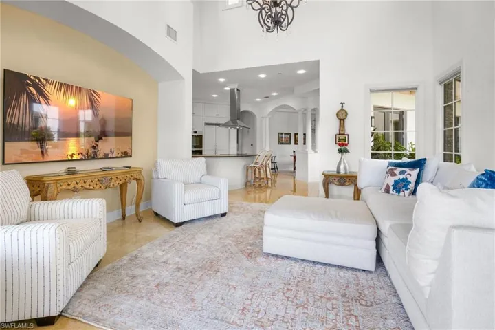 Living area featuring arched walkways, a high ceiling, and recessed lighting