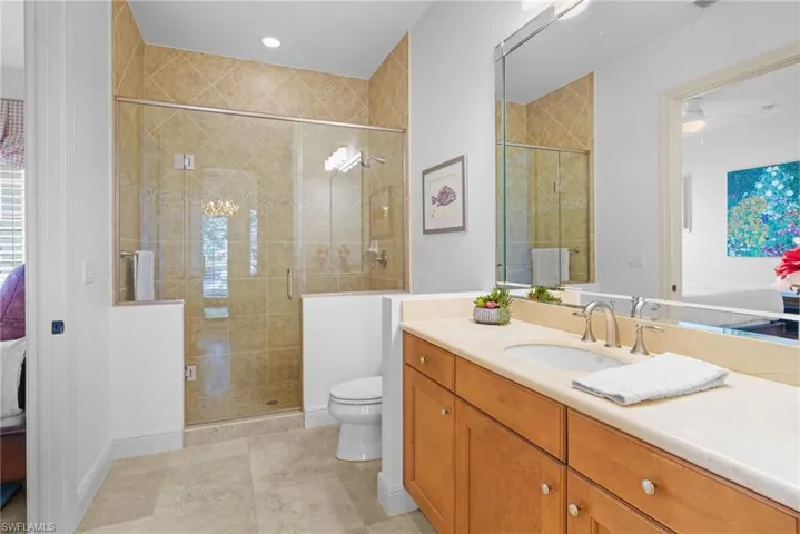 Ensuite bathroom featuring vanity, a shower stall, light tile patterned floors, and recessed lighting