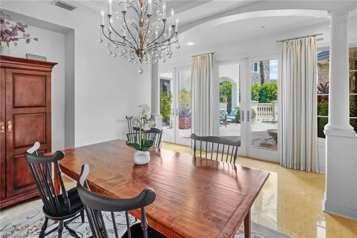 Dining space featuring french doors, ornate columns, recessed lighting, arched walkways, and a chandelier
