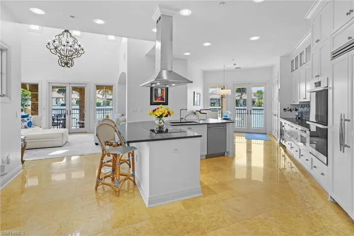 Kitchen with a chandelier, a kitchen bar, french doors, island exhaust hood, and hanging light fixtures