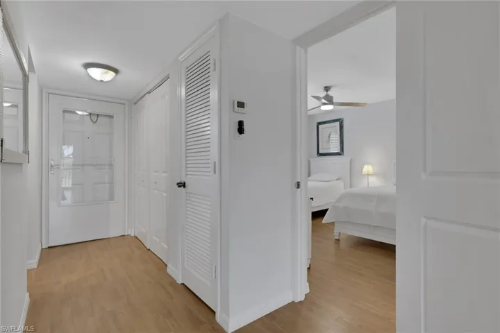 Entryway featuring wood-finish flooring, white walls, and a white front door with a glass panel